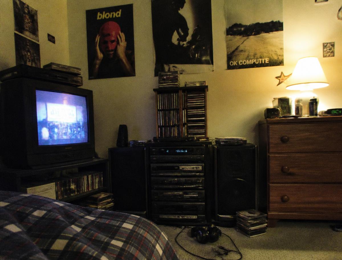 A late-1990s bedroom stereo, CD collection and CRT television photographed with flash